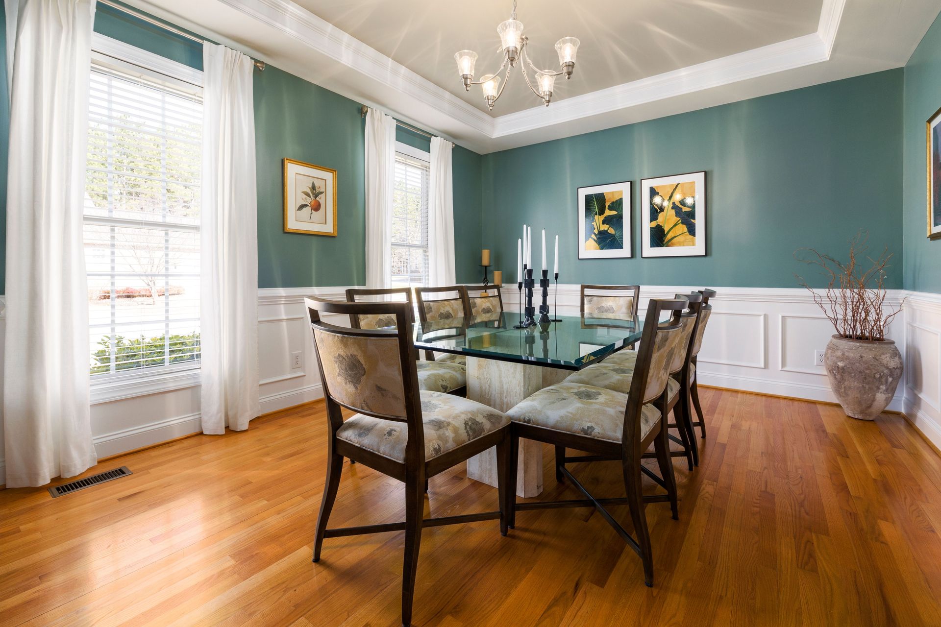 Beautifully styled dining room with a glass table, elegant chairs, and artistic wall decor.